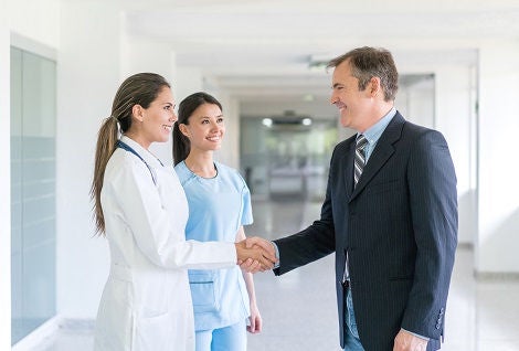 Doctor greeting health insurance agent with a handshake at the hospital