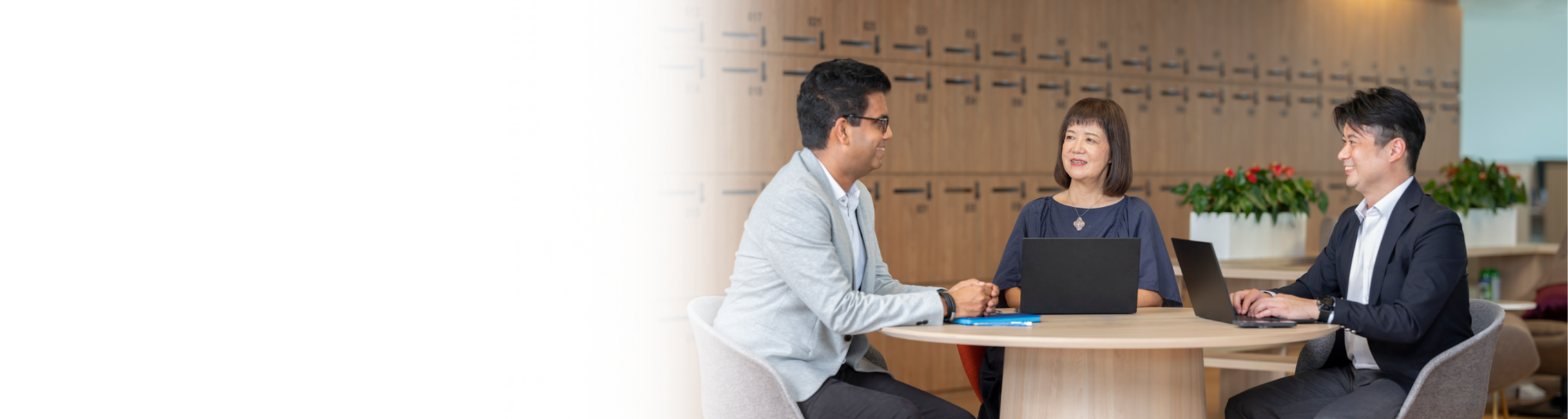 Santen colleagues of diverse ethnicities having a discussion while seated with their laptops and notebooks at a collaboration workspace in the office.