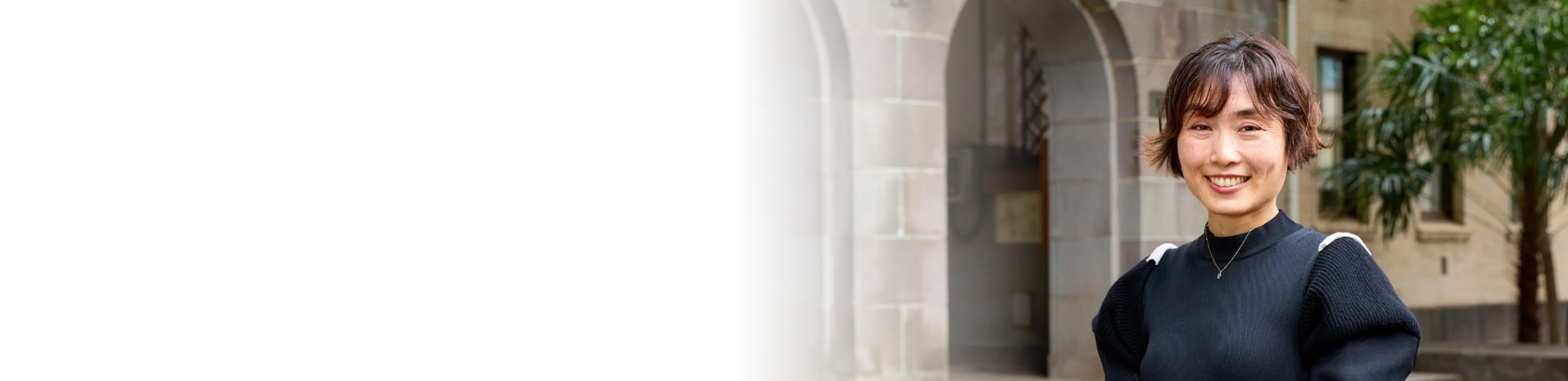 キャンパス内の歴史ある建物の前でほほえんでいる伊藤教授の写真