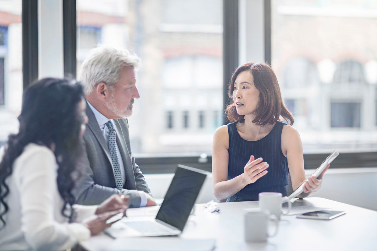 Businesswoman discussing with colleagues. Entrepreneurs are planning in board room. They are sitting at table in office.