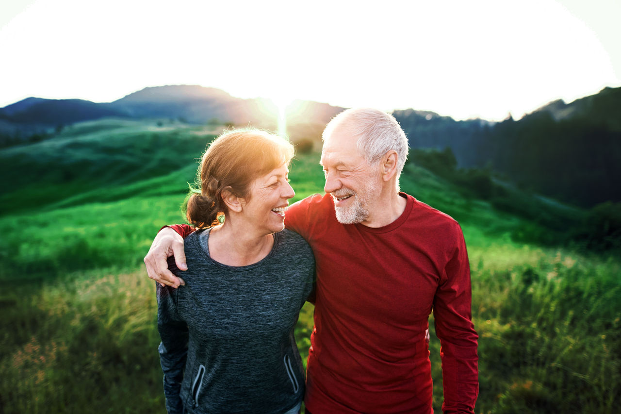 A portrait of old man and woman resting after doing sport outside in the countryside.