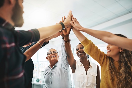 Cropped shot of a group of designers high fiving during a meeting in the boardroom